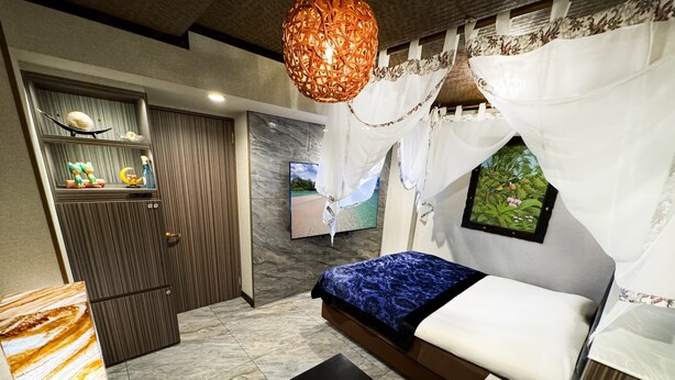 Un dormitorio moderno con cama, televisor, pared decorativa y una lámpara de techo original.