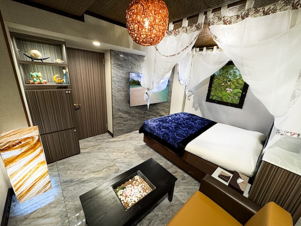 Un dormitorio moderno con cama, televisor, pared decorativa y una lámpara de techo original.