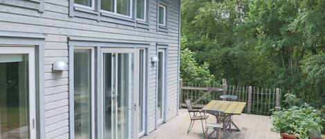 A two-story house with a deck, sliding glass doors, and a fenced garden area.