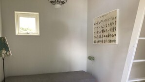 A small room with a single bed, a window, a wall-mounted light fixture, and a bird illustration on the wall. - 4 Star Holiday Home in Falkenberg (Falkenberg)