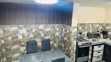 A kitchen with a stone backsplash, a gas stove, a microwave, and a coffee maker.