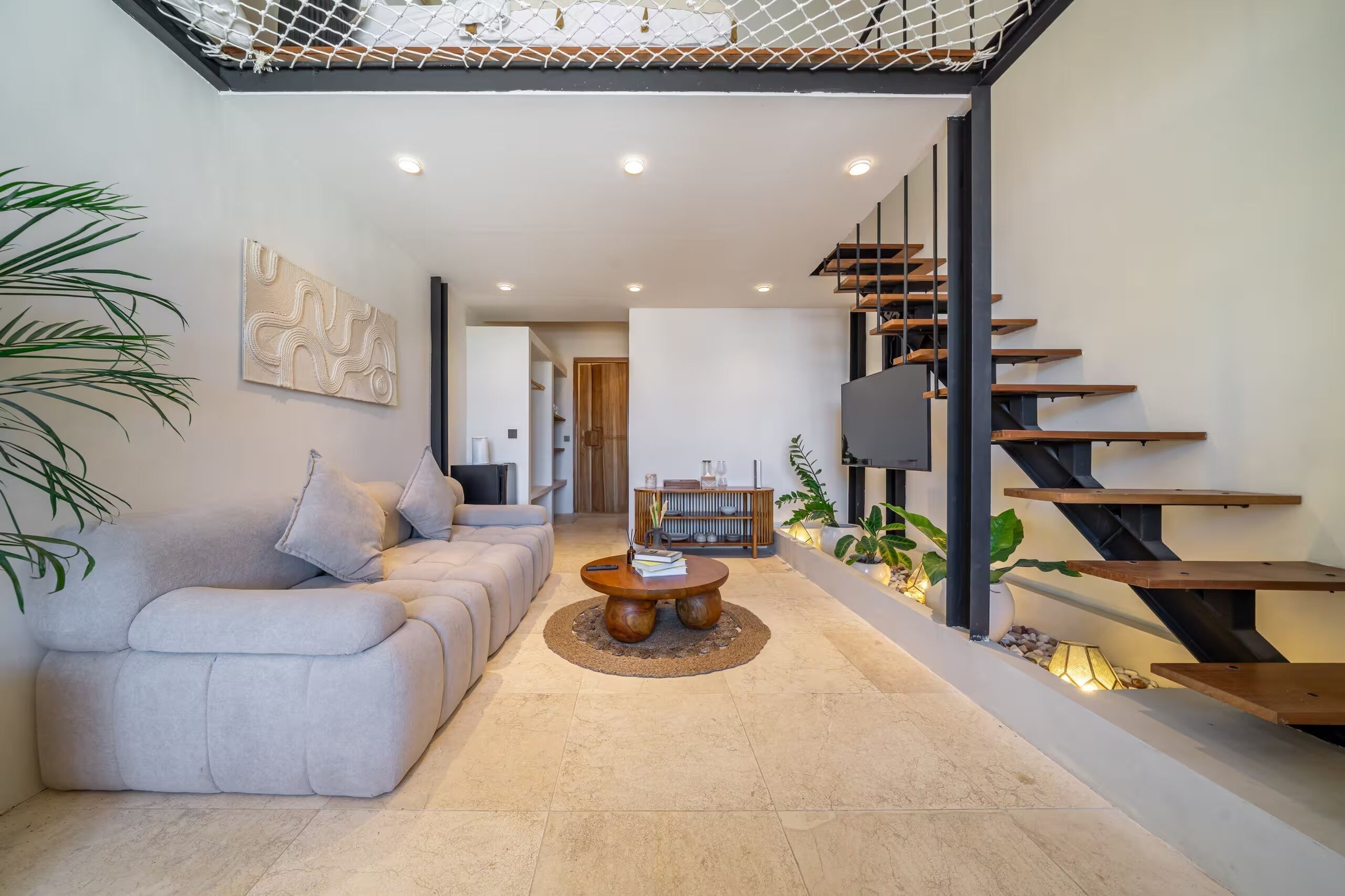 Un salon moderne avec un canapé, une table basse et un escalier.