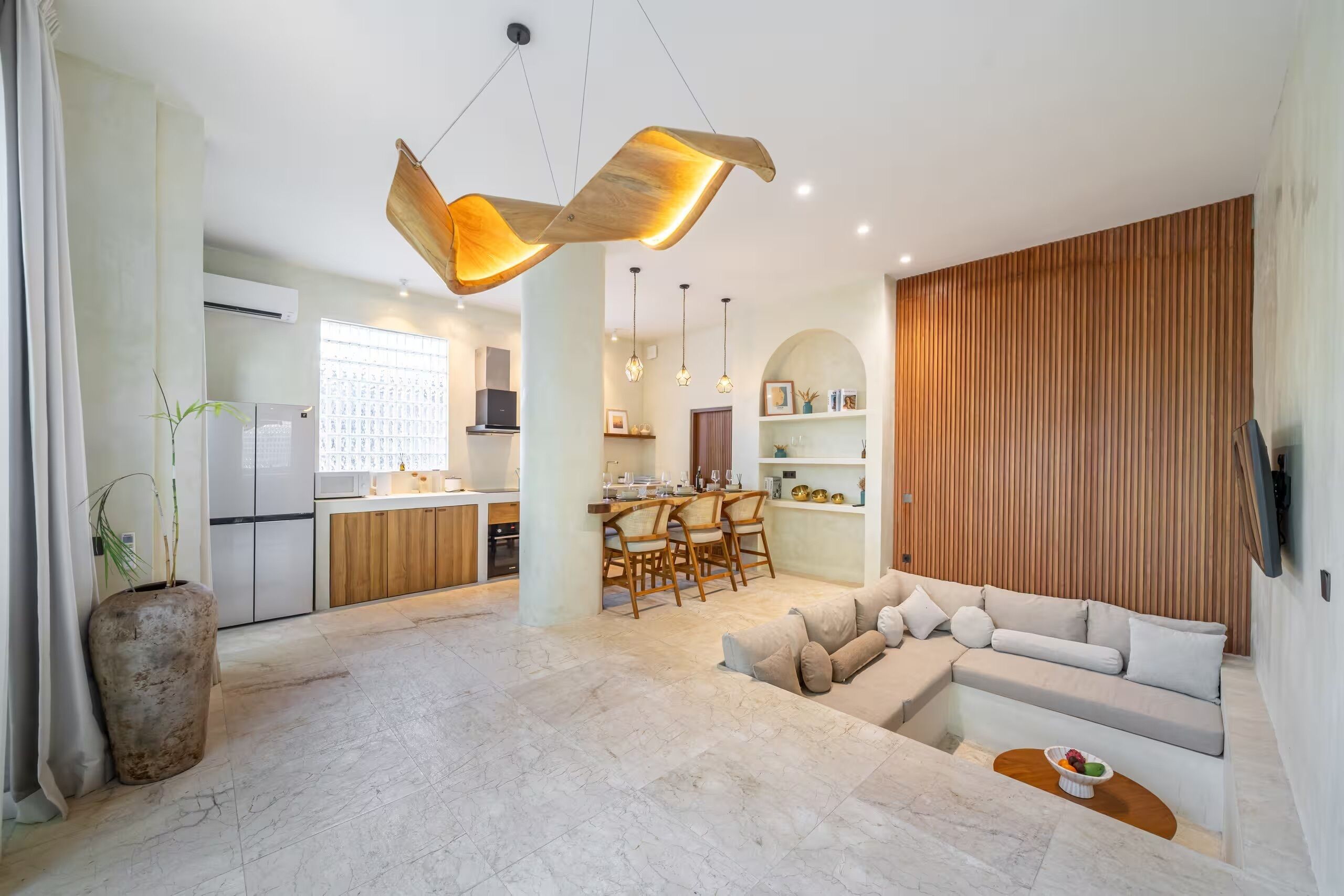 Una cocina moderna con comedor, un sofá grande y un televisor en la pared.