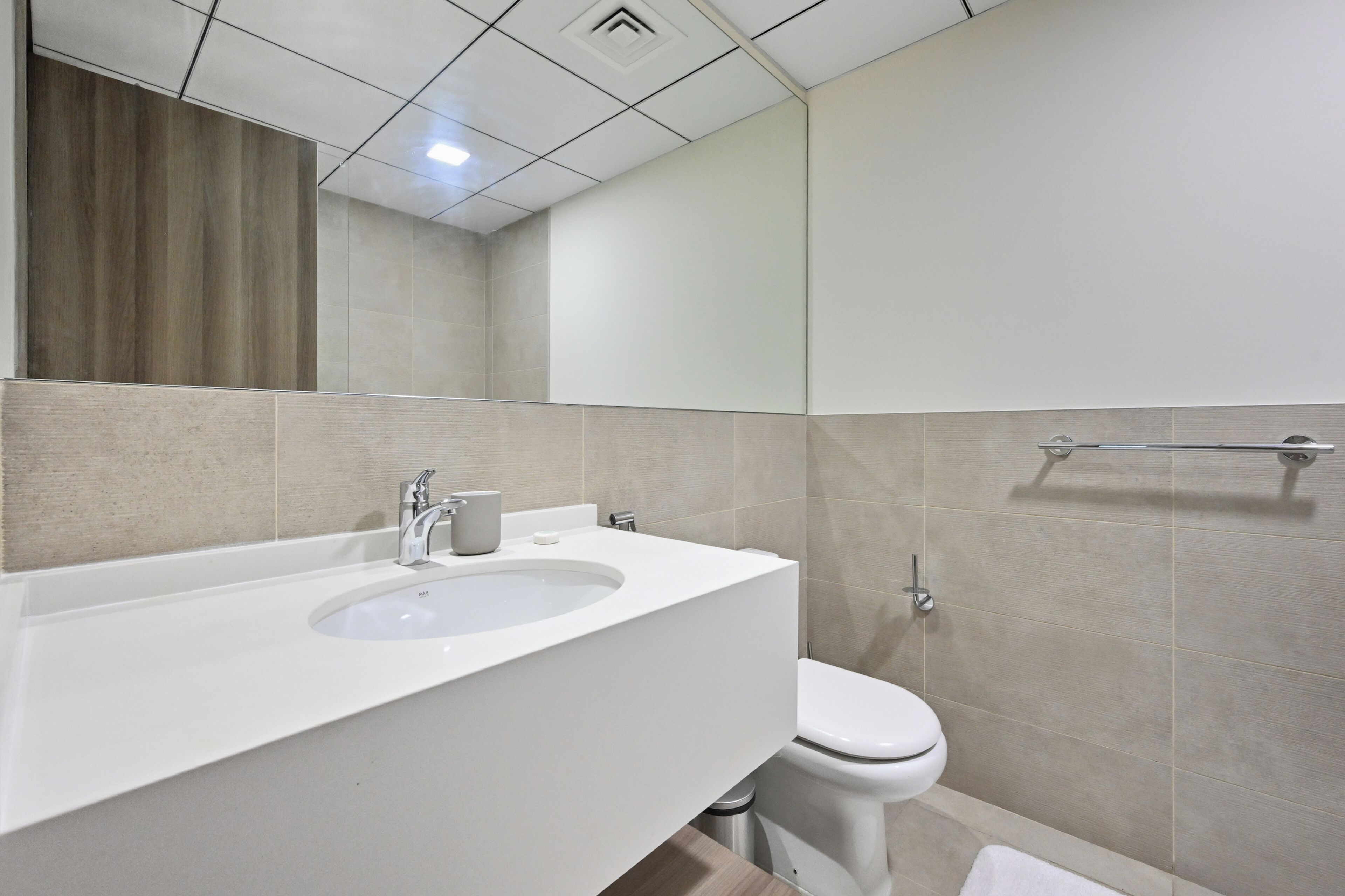 Une salle de bain équipée d’un lavabo, d’un miroir, de toilettes et d’un porte-serviettes.