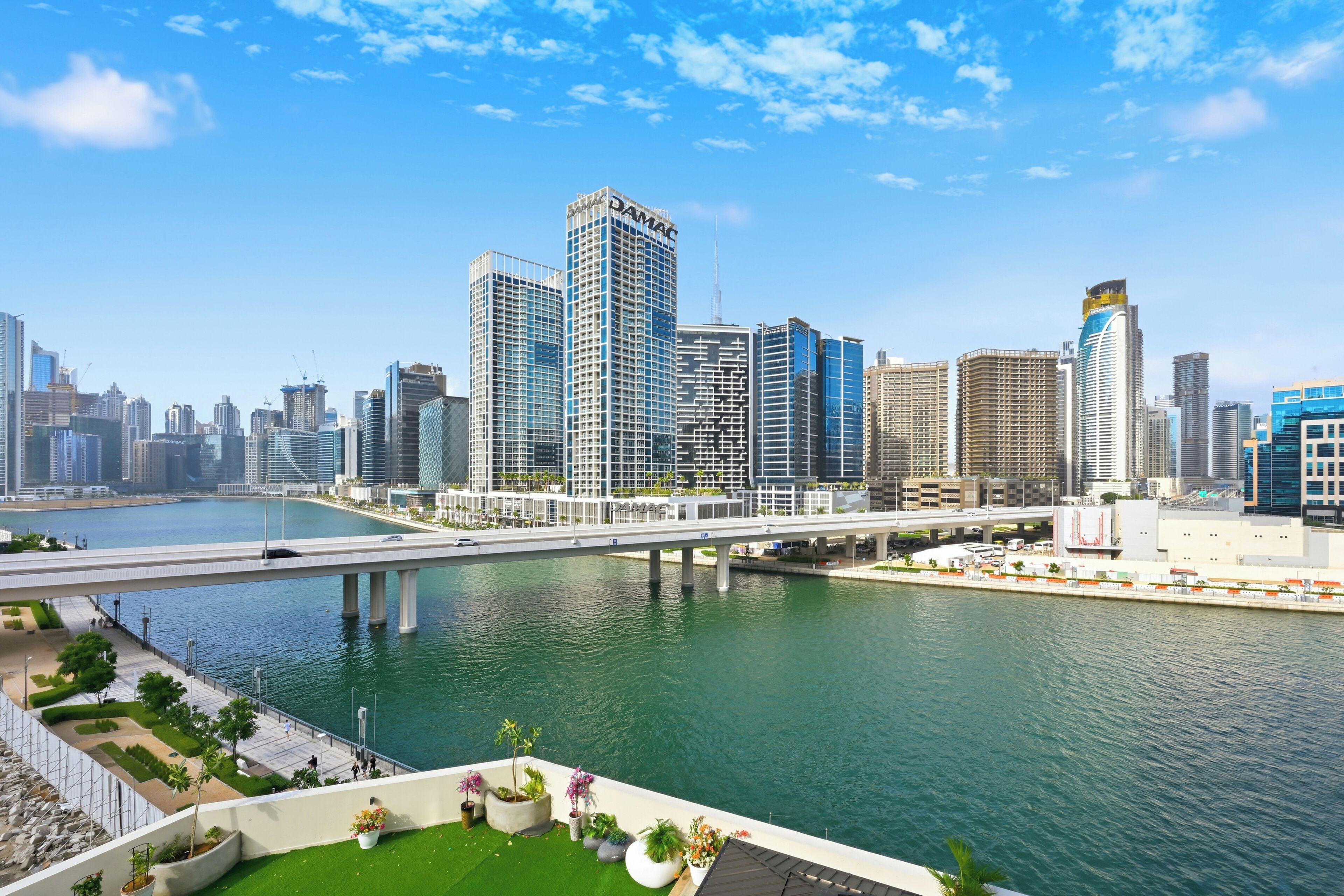 A city skyline with modern high-rise buildings, a river, and a bridge.