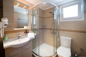 Ein modernes Badezimmer mit einer gläsernen Dusche, einem weißen Waschbecken und einer Toilette.