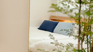 Cama com roupa de cama branca, cabeceira de madeira e duas almofadas.