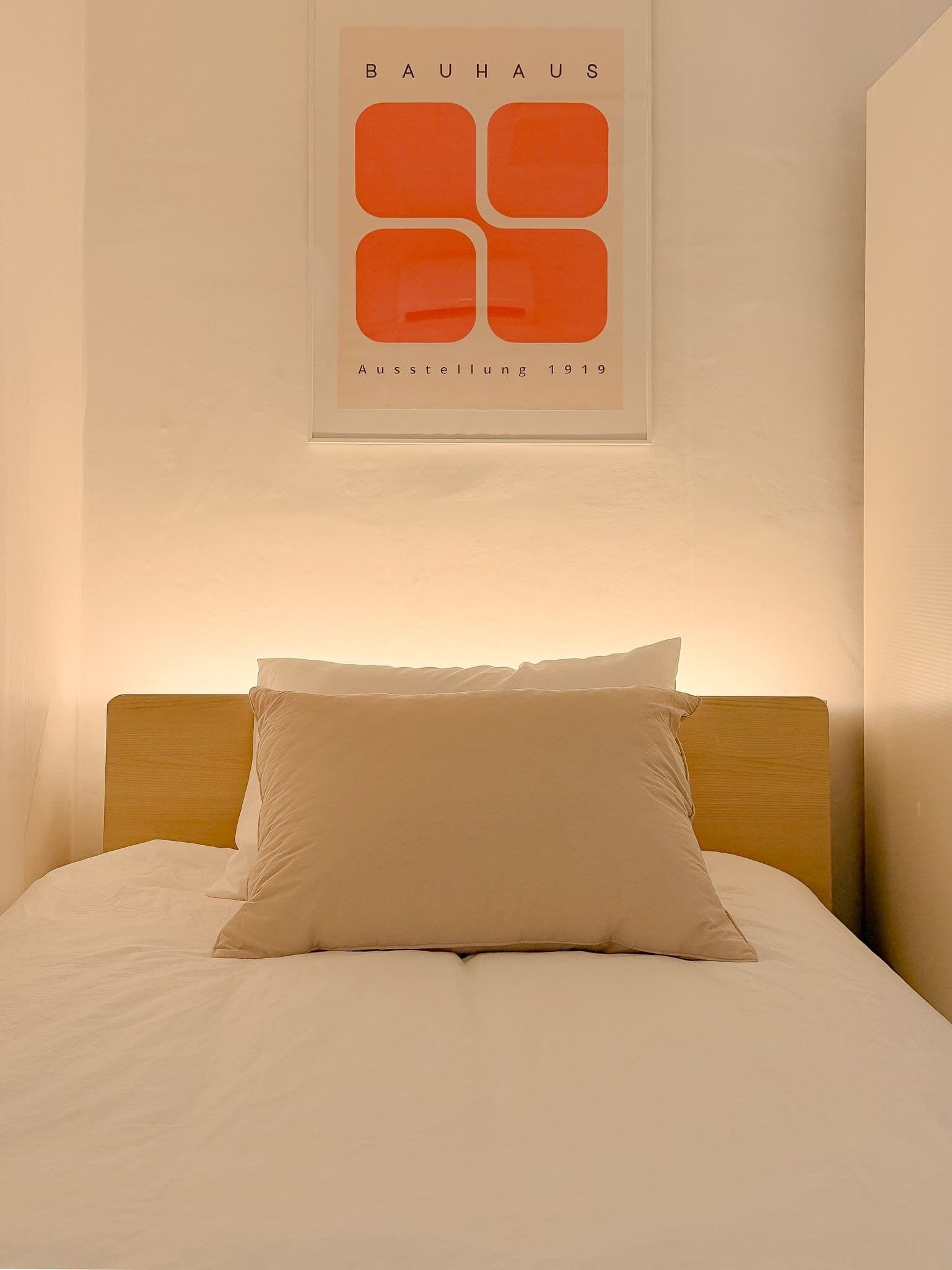 Ett hotellrum med en säng, en träpanel som huvudgavel och ett inramat konstverk på väggen.
