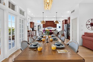 A spacious dining area with a long wooden table set for a meal, surrounded by wicker chairs. - Private Pool + Dock + Bay Views | Walk to Beach + Times Square | Sunset Slip (Fort Myers Beach)