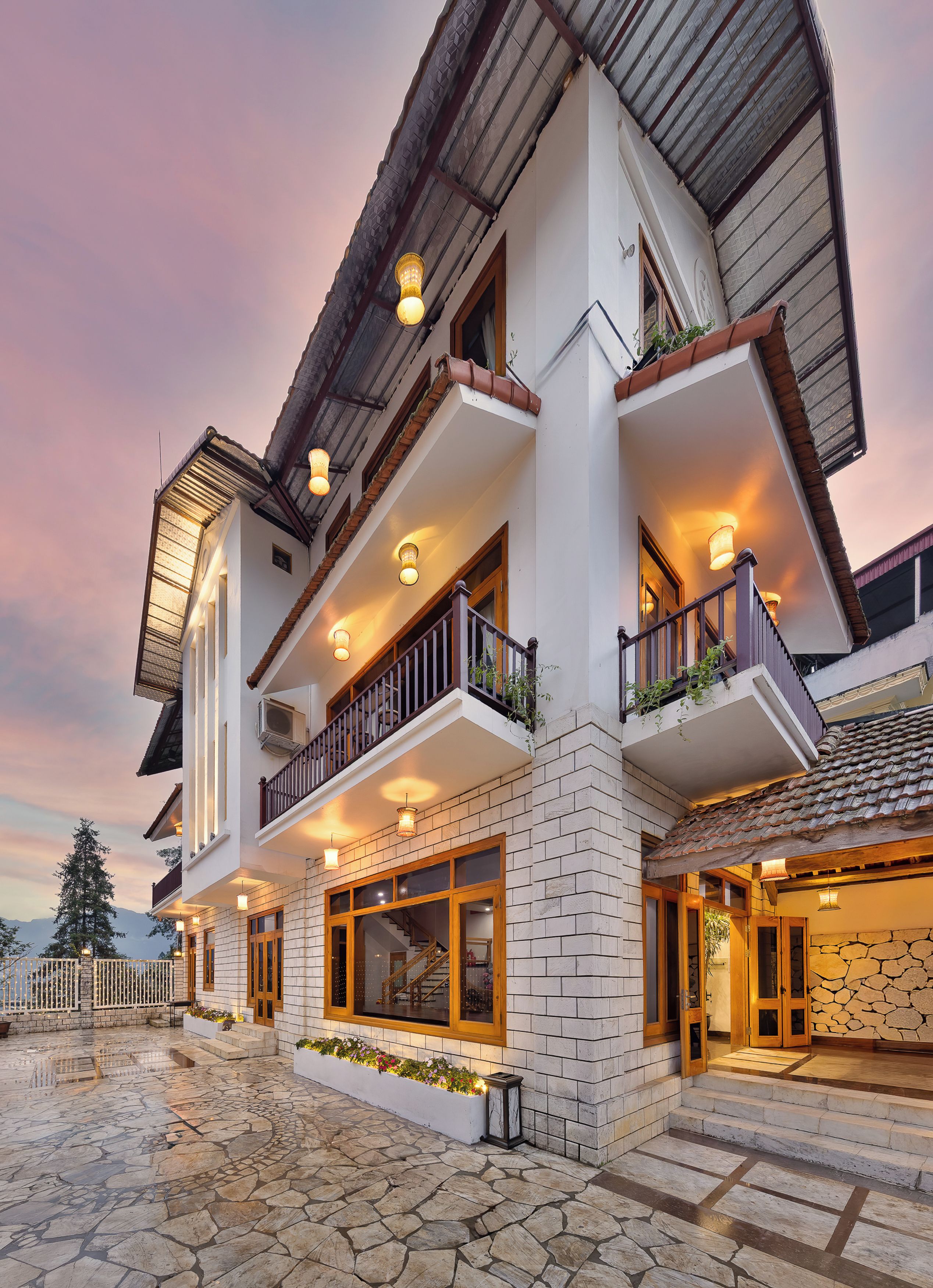 A multi-story building with balconies, large windows, and a stone-paved entrance.
