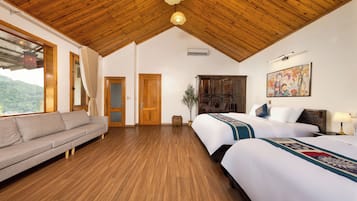 Una habitación de hotel con techo de madera, un sofá, una cama con colcha estampada, un cuadro en la pared y vistas al exterior.