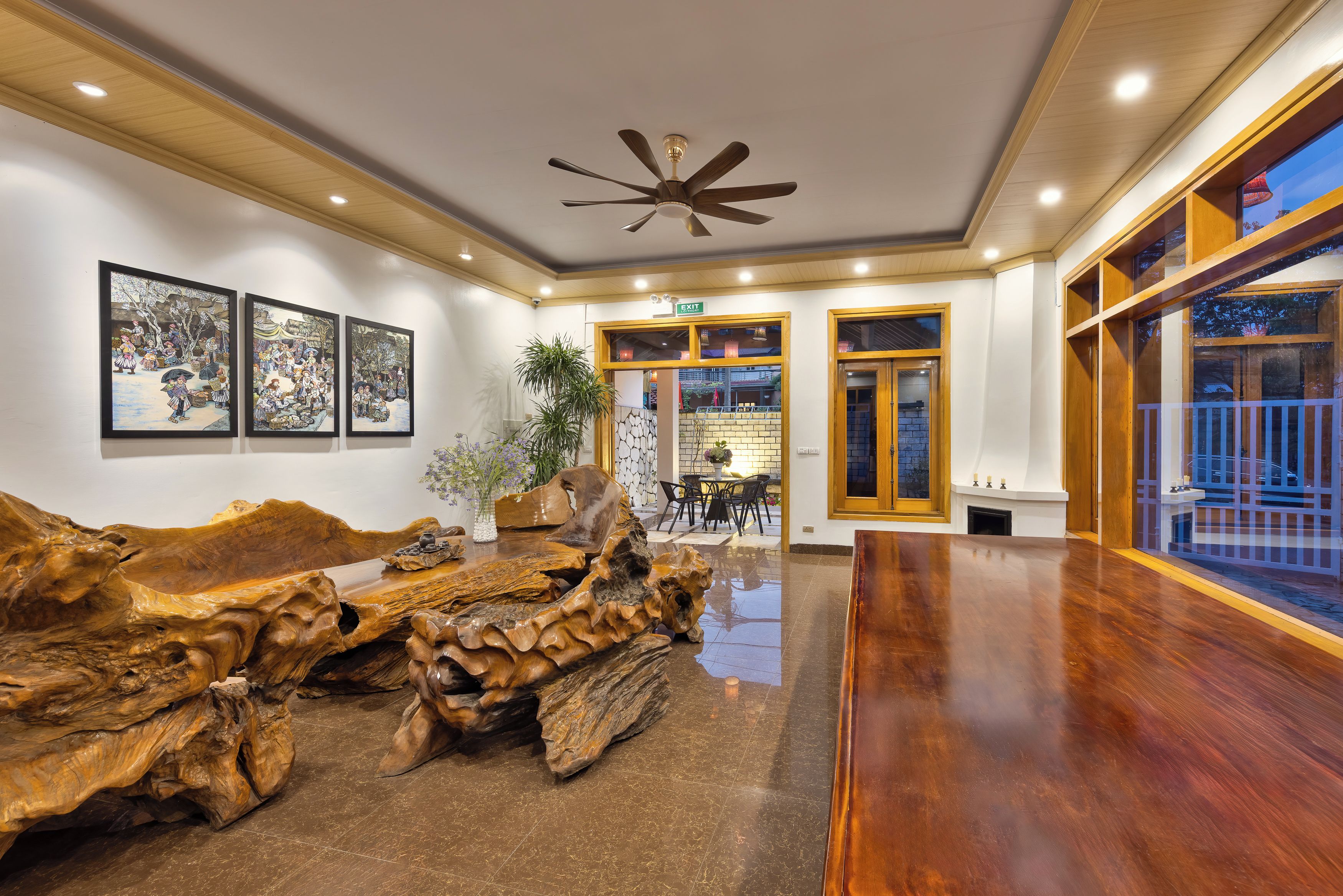 A spacious lobby with a wooden coffee table, framed artwork on the wall, and a ceiling fan.