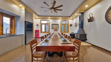 Un comedor con una larga mesa de madera, sillas, un ventilador de techo y una chimenea.
