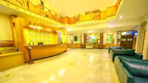 A hotel lobby with a reception desk, seating area, and a second-floor balcony. - Grand Palace Yercaud (Yercaud)