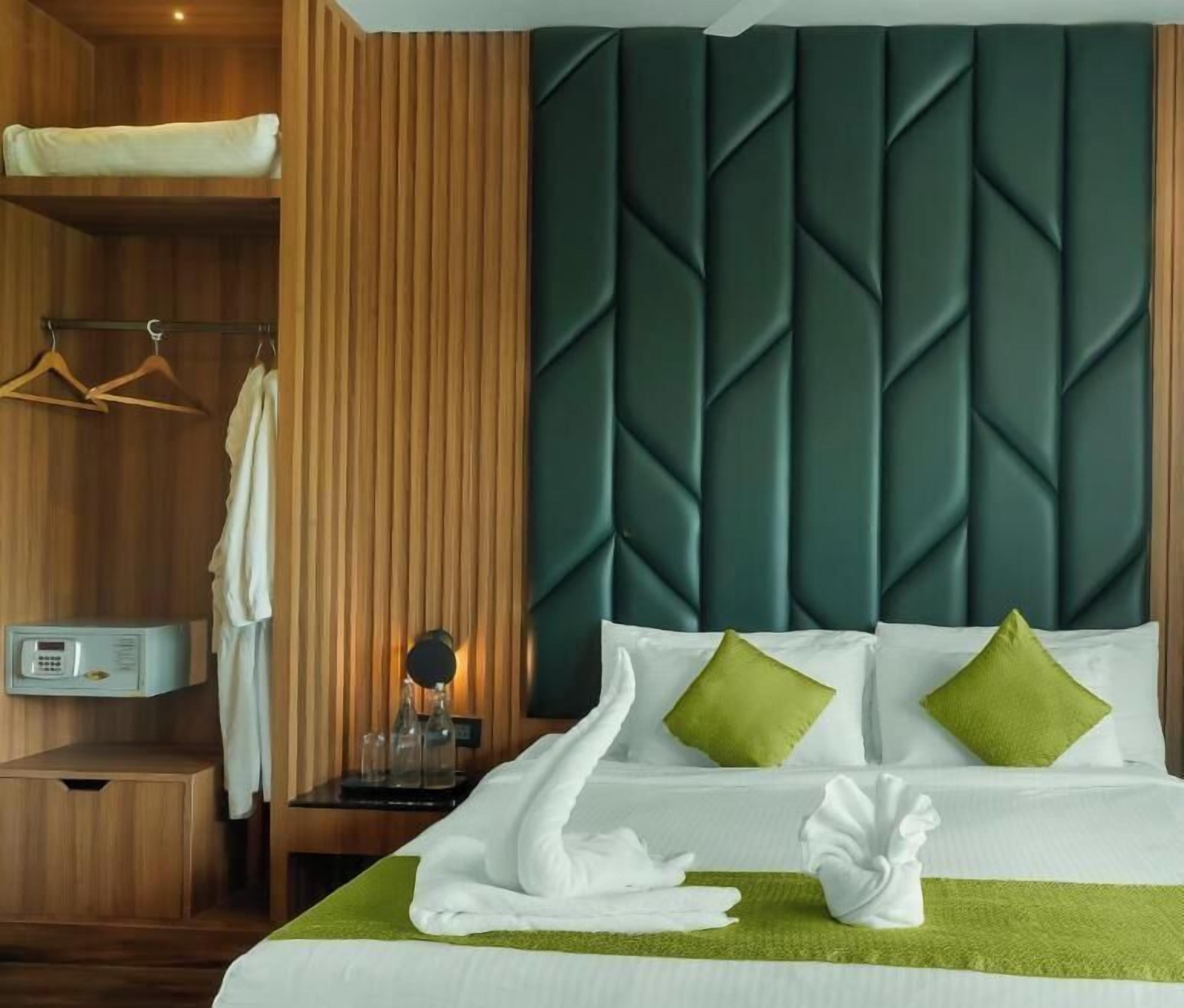 Hotellihuone, jossa on sänky, yöpöytä, yökaappi, vaatekaappi ja peili.