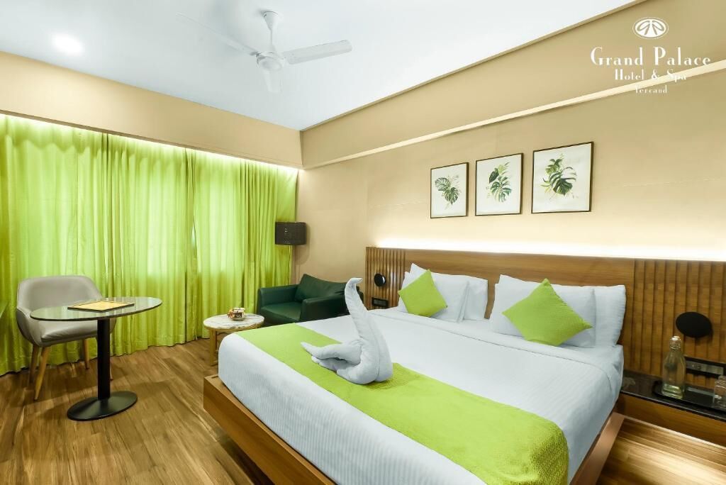 Habitación de hotel con cama, una silla, una mesita y cortina verde.