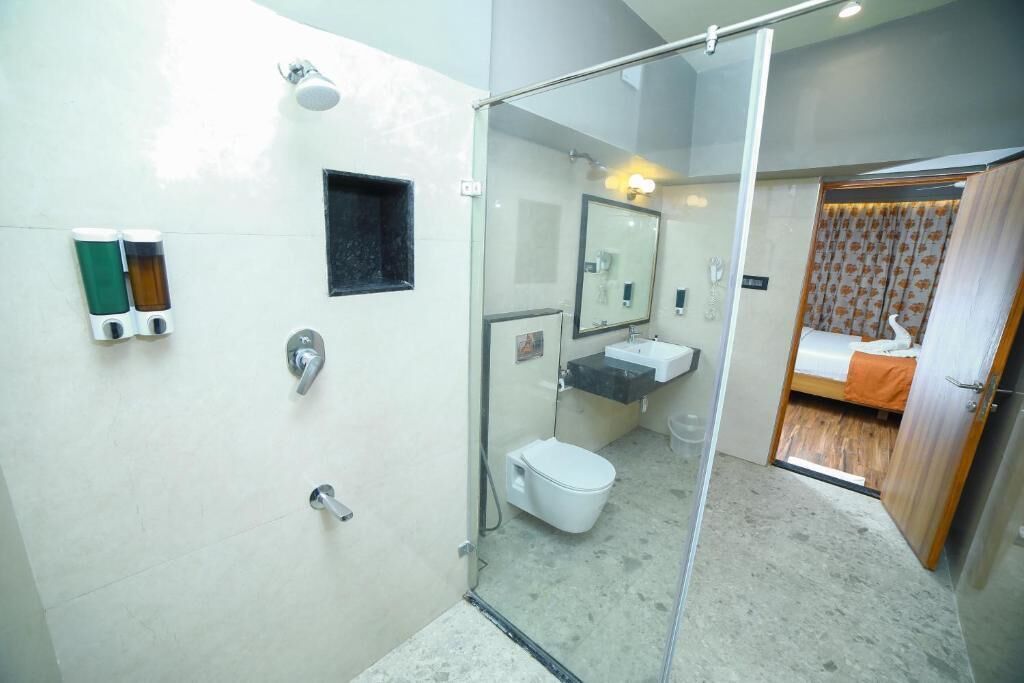 A bathroom with a shower, toilet, sink, and a small mirror.