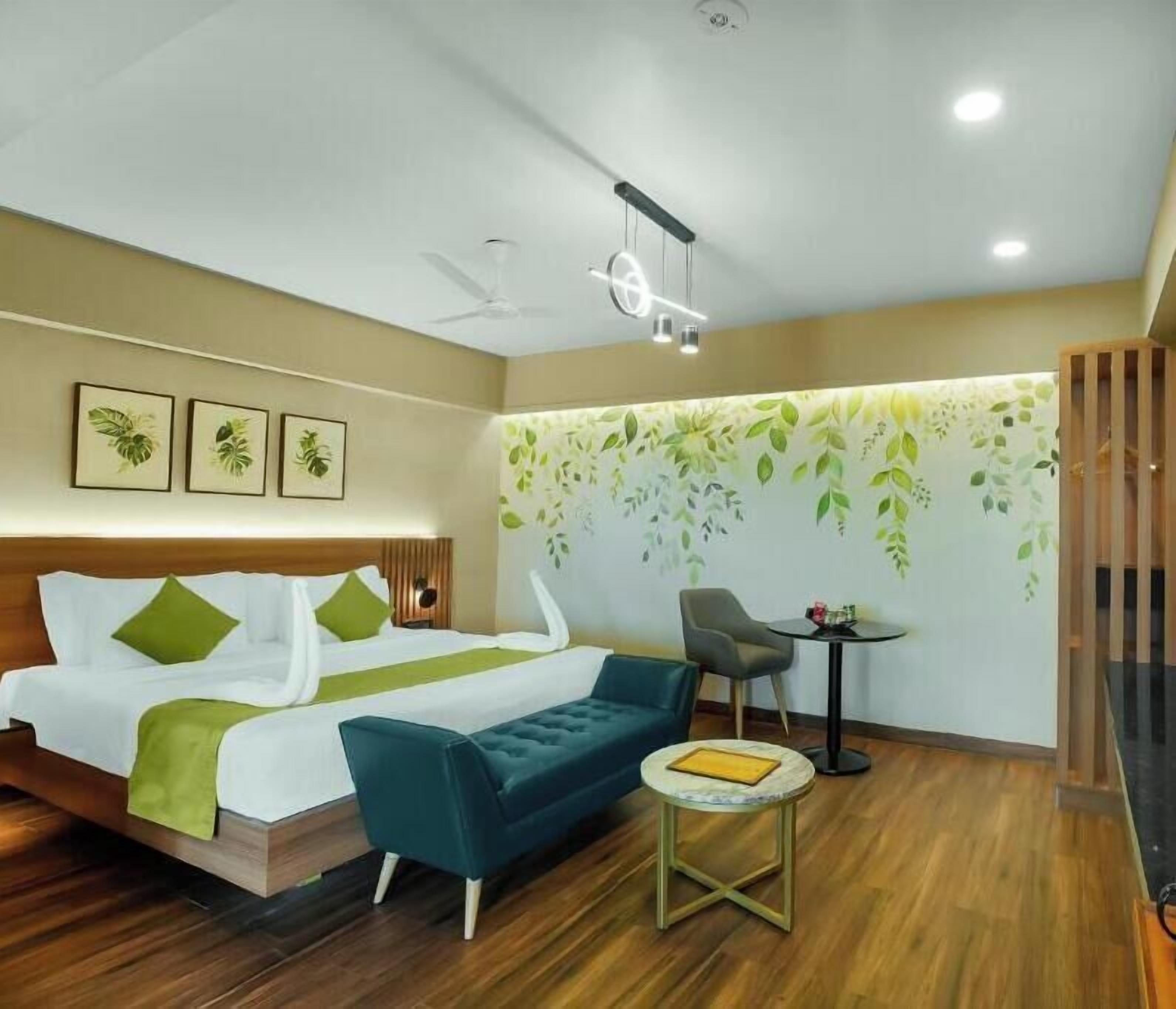 Una habitación de hotel con cama, sofá, mesita y silla.