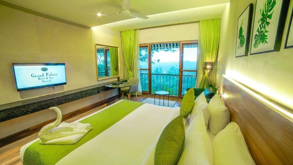 A hotel room with a bed, a TV, a balcony with a view, and a desk.