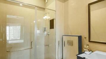 Une salle de bain avec une douche à parois de verre, un lavabo blanc et un miroir.