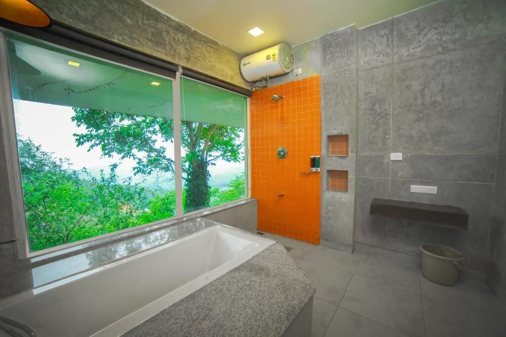 Un baño con bañera, ducha y ventana con vistas al verdor.