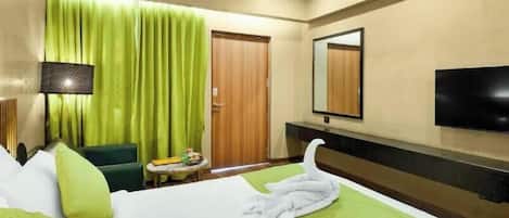 A hotel room with a bed, a desk, a chair, a television, and a mirror.