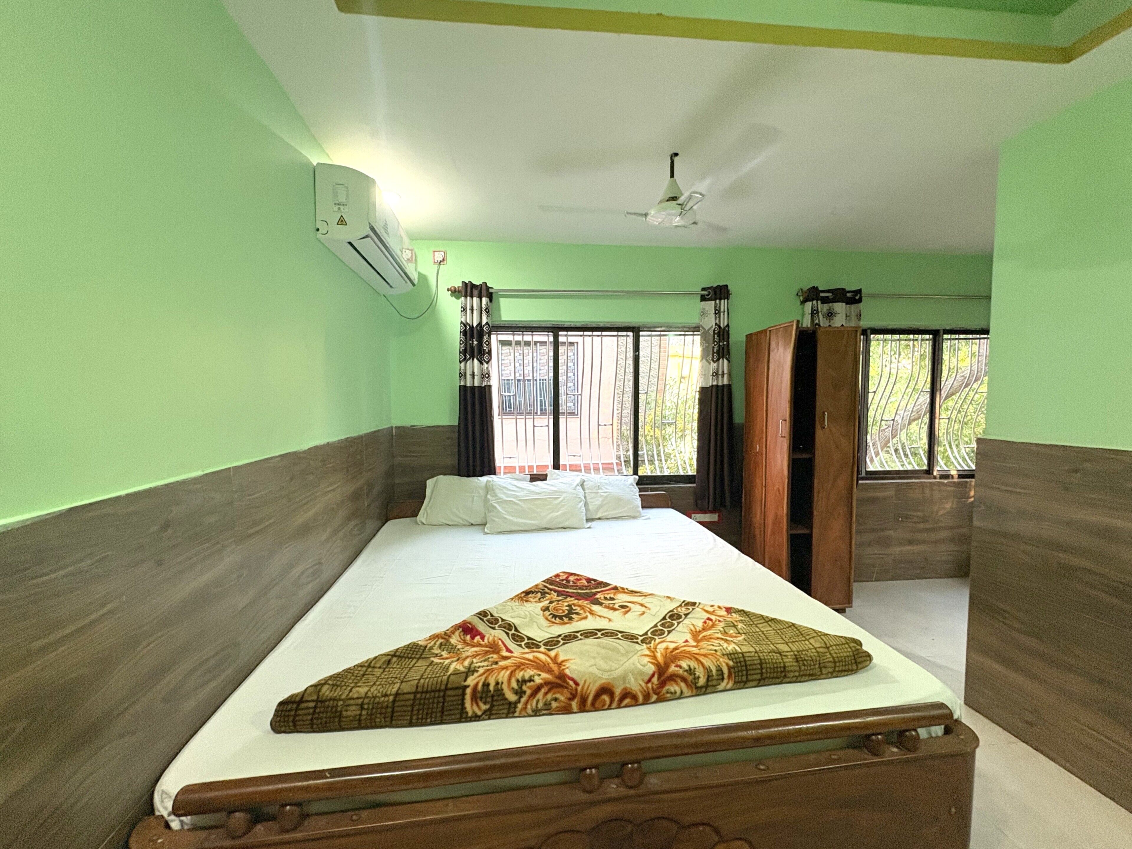 Una stanza con un letto, condizionatore d'aria, una finestra con inferriate e una ventola a soffitto.