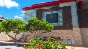 Un edificio moderno con un llamativo letrero de 'T Galleria', fachada de piedra y una escalera que conduce a una entrada.