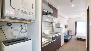 Habitación de hotel pequeña con kitchenette, una cama y un baño.