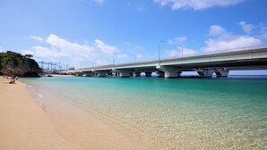 Una playa con agua turquesa cristalina, una orilla de arena y un puente con varios pilares.