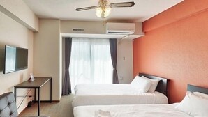 Habitación de hotel con dos camas, un escritorio, un televisor y un equipo de aire acondicionado.