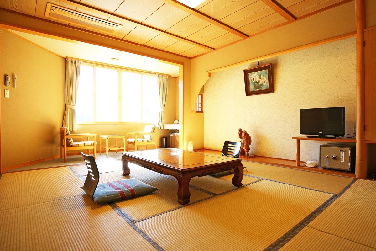 A traditional Japanese-style room with tatami flooring, a low table, and a television.