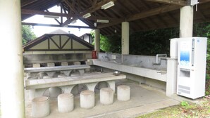 A public outdoor restroom with a large sink, multiple urinals, and a water dispenser.