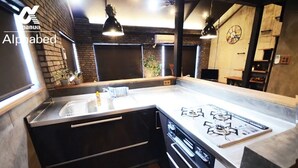Een kleine keuken met een gasfornuis, zwarte kastjes en een aanrecht.