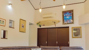A living room with a brown leather sofa, a glass coffee table, and a wall-mounted surfboard.