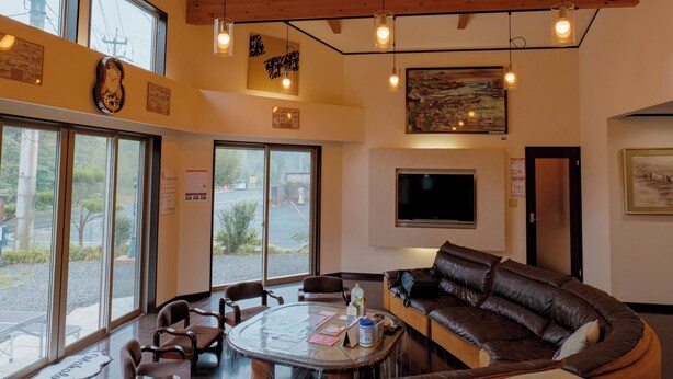 A cozy interior with a round glass table, leather sofa, and wooden ceiling beams.