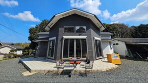 A modern two-story house with a large front porch, a garage, and a gravel driveway.