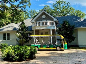 A two-story house with a balcony, a green and yellow vehicle parked in front, and a brick exterior. - Haga Farm & Glamping (Haga)