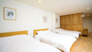 A hotel room with three single beds, a wooden partition wall, and a sofa. - K's Hotel (Takamatsu)