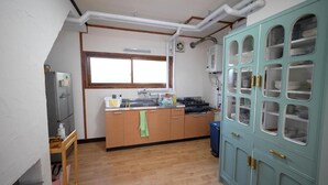 A kitchen with a window, wooden cabinets, a sink, and a teal cabinet with glass doors.
