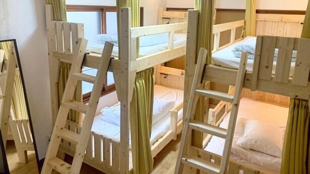 Bunk beds with wooden railings, a window with curtains, and a mirror on the wall.