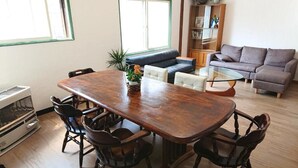 A dining area with a wooden table and chairs, a sofa, and a bookshelf.