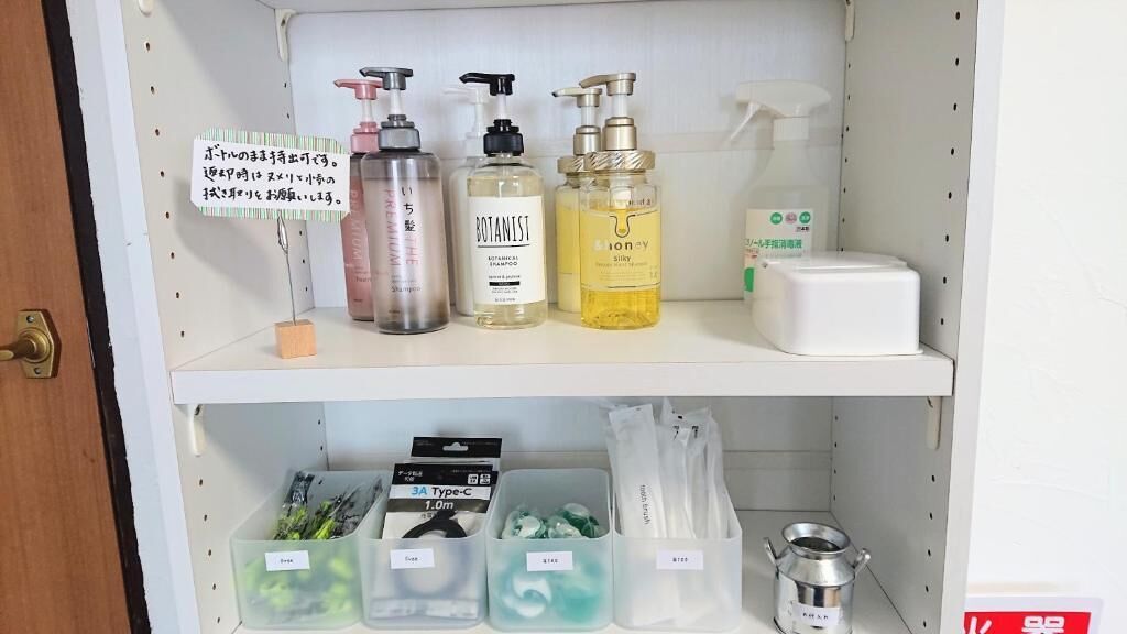 Un estante con varios artículos de aseo personal, incluyendo una botella de champú Botanist, una botella de champú de miel y una botella de loción.