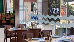 A restaurant with tables and chairs, an exit sign, and a wall with a logo.