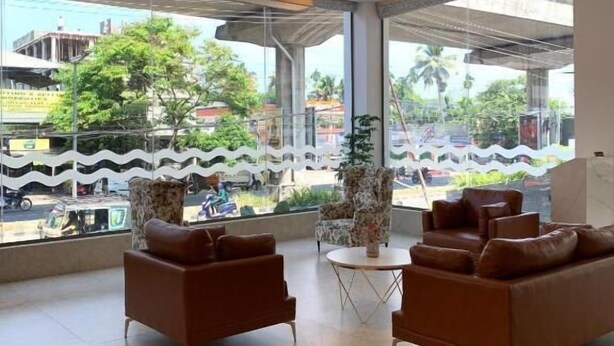 A modern lobby with leather sofas, a round table, and large windows offering a view of the street.