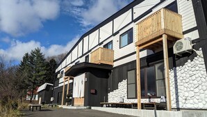 A modern building with a balcony, a stone wall, and a clear sky.