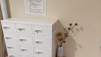 A white storage unit with multiple compartments, a vase with dried flowers, and a wall-mounted sign with text.