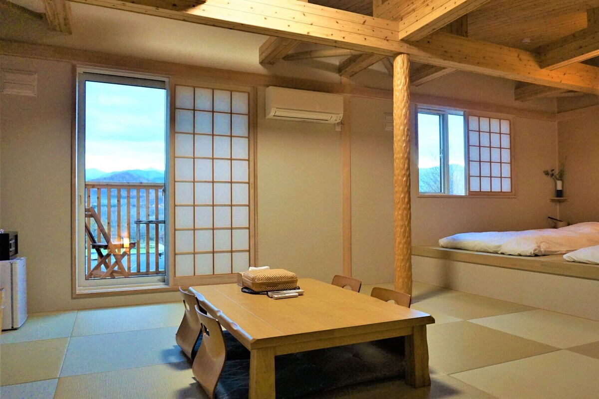 Una habitación tradicional japonesa con suelo de tatami, una mesa baja y puertas correderas.