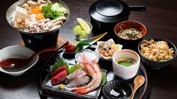 Diversos platos japoneses, como sashimi, arroz y sopa, sobre una mesa de madera.