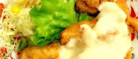 Un plato con pollo frito, ensalada de col y una ensalada de hojas verdes.